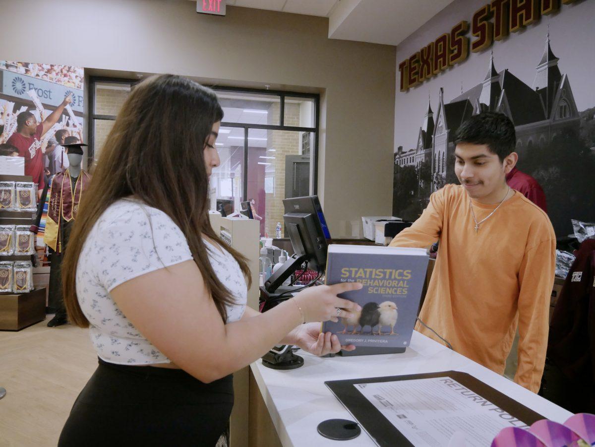 Texas State health sciences sophomore Kassandra Villarreal checks the price of a textbook in The Bobcat Store located on the 2nd floor of LBJ Student Center, Friday, March 31, 2023.