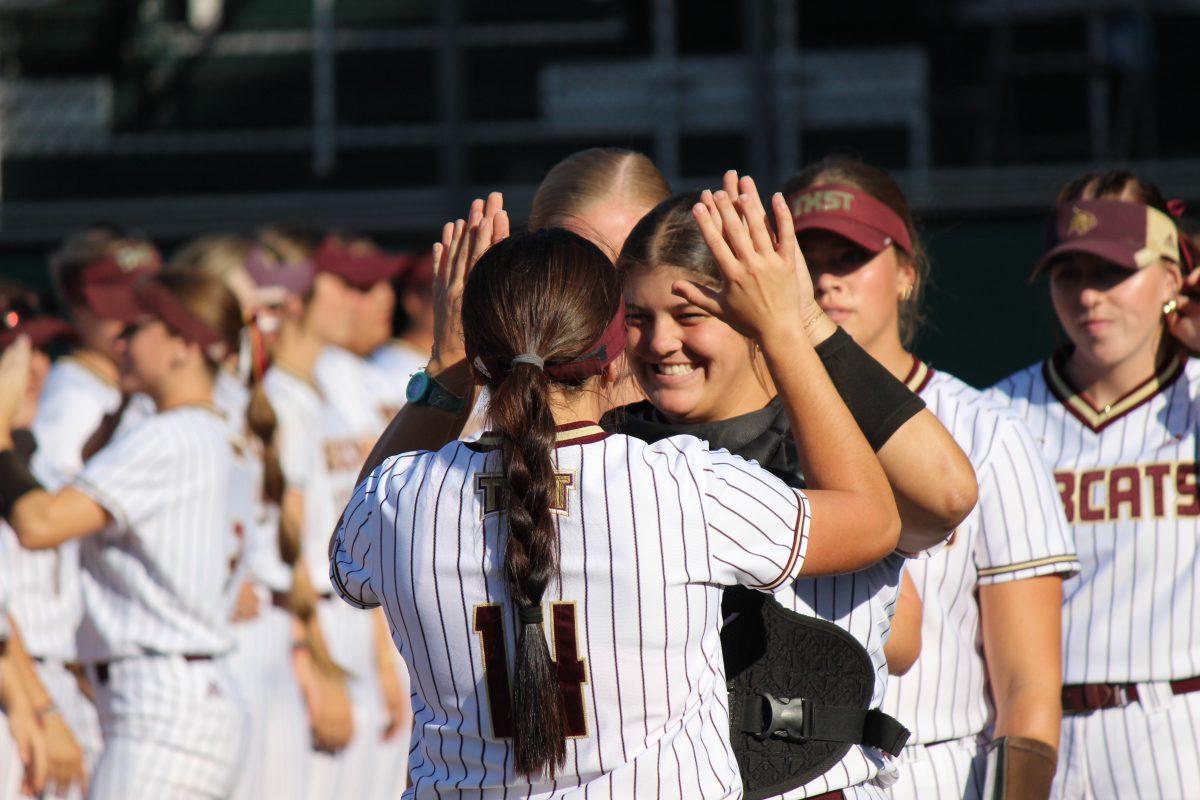 Texas State junior Anna Jones (14) and freshman catcher Karmyn Bass (10) give each other encouragement before their name gets called and they walk onto the field, Tuesday, April 12, 2023, at Bobcat Softball Stadium.