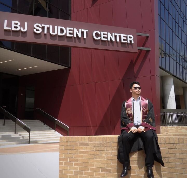 Texas State journalism senior poses on a ledge for his graduation photos, Sunday, March 26, 2023, outside LBJ Student Center.