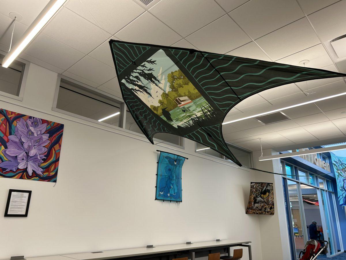 Local San Marcos artist Topher Sipes kite hangs from the ceiling in front of kites from the Sacred Springs Kite Exhibition, Sunday, June 4, 2023, at the San Marcos Public Library.