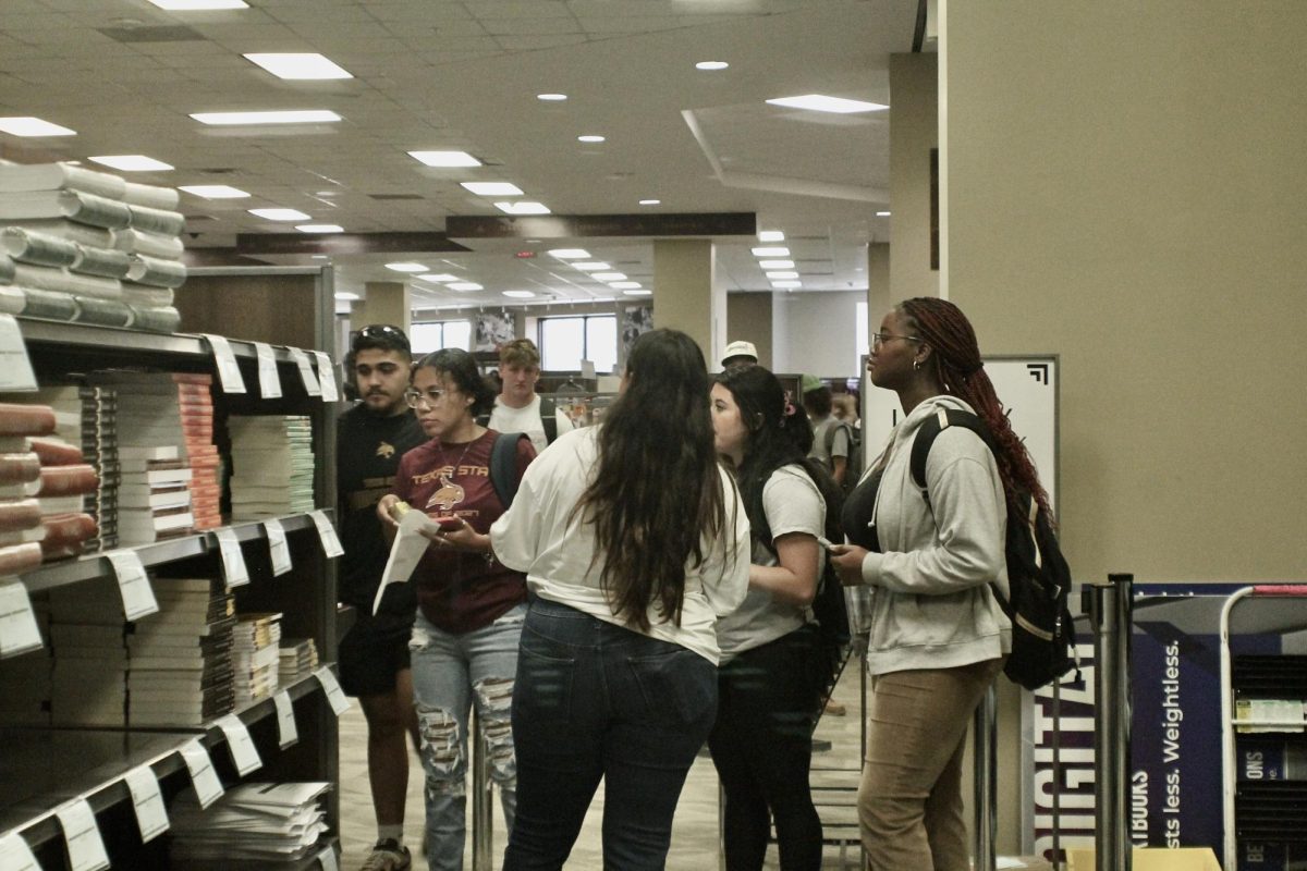 Sales associate Becca Muro helps students find textbooks, Monday, Aug. 21, 2023 in San Marcos.