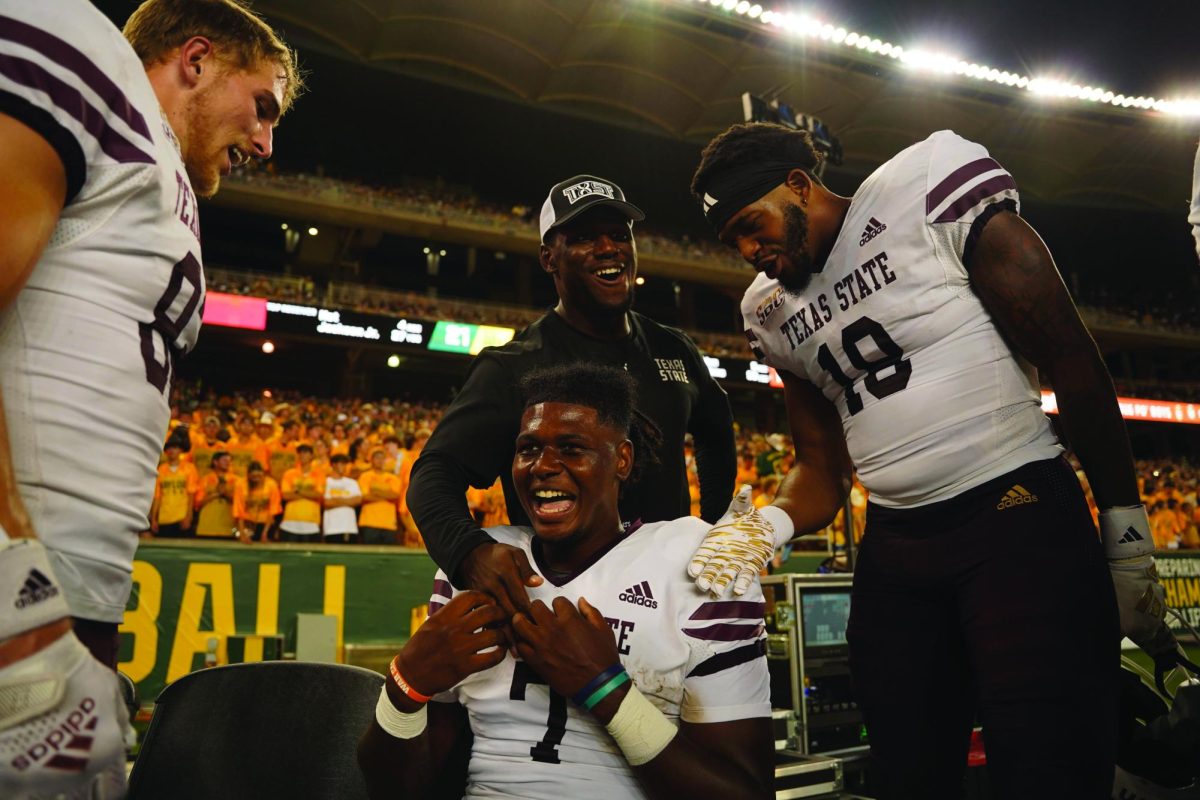 Texas State offensive assistant coach Lindsey Scott Jr. embraces redshirt sophomore quarterback T.J. Finley (7) during the Baylor game, Saturday, Sept. 2, 2023, at McLane Stadium in Waco, Texas. 