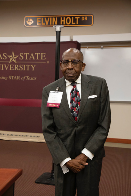 Dr. Elvin Holt standing at a sign for a street named after him on the Round Rock campus, Friday, Nov. 12, 2021 at Texas State University - Round Rock Campus. 