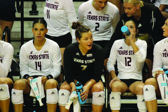 Texas State senior setter Ryann Torres (14) and junior defensive specialist Jacqueline Lee (7) discuss strategy with fellow teammates, Thursday, Aug. 19, 2023, at Strahan Arena. 