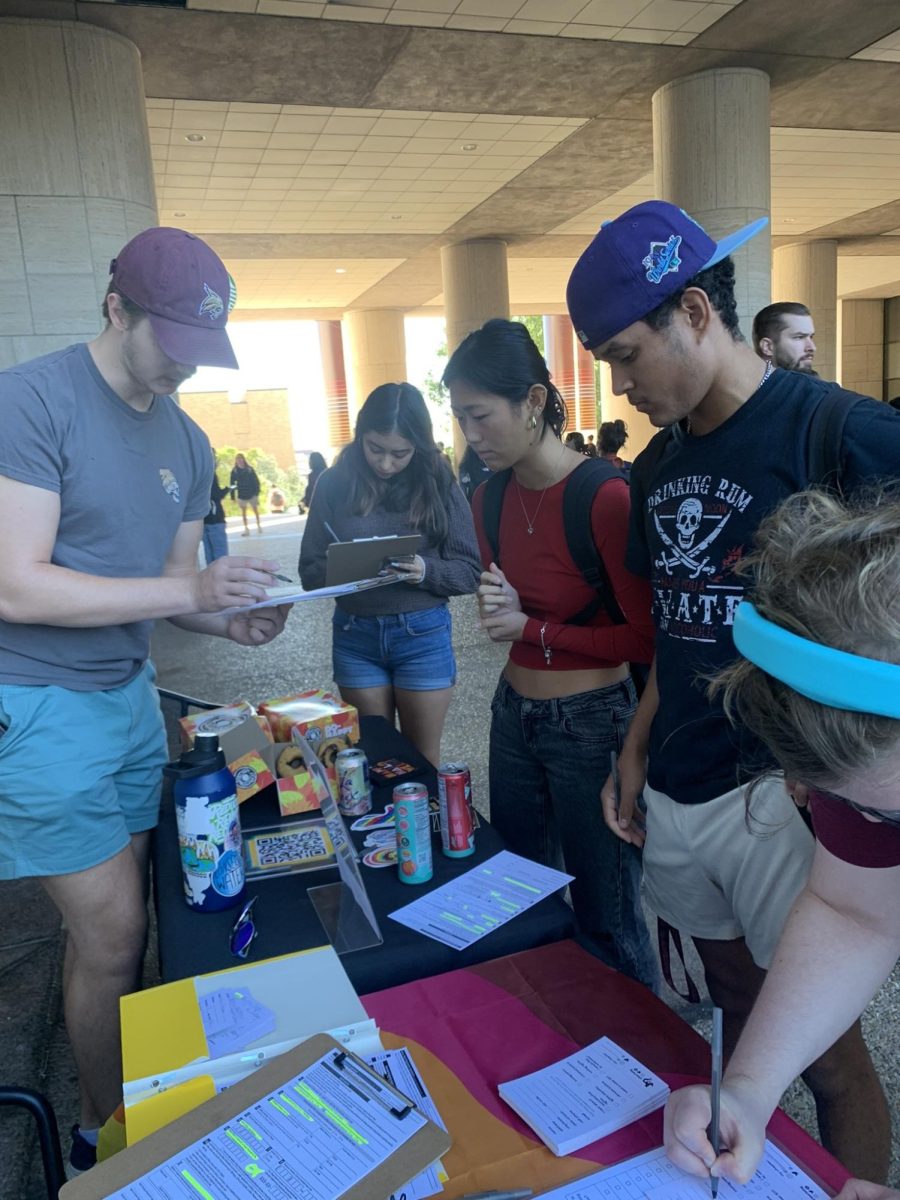 Public administration senior Jacob Graybill (left) assists students with voter registration forms, Monday, Oct. 9, 2023, in front of Alkek Library.