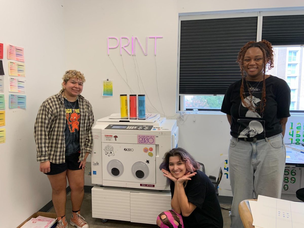 Mars Velasquez (left), Zainab Alhatri (center) and Chinny Egbuna (right) standing next to risograph printer in the fabrication room, Dec. 1, 2023, in the Joann Cole Mitte building.