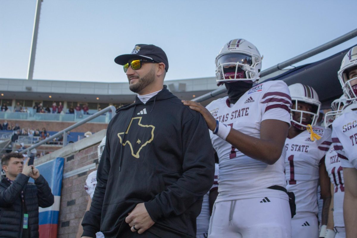 Texas State Head Coach G.J. Kinne walks out of the tunnel alongside reshirt sophomore quarterback T.J. Finley (7) ahead of the SERVPRO First Responder Bowl game versus Rice, Tuesday, Dec. 26, 2023, at Gerald J. Ford Stadium.