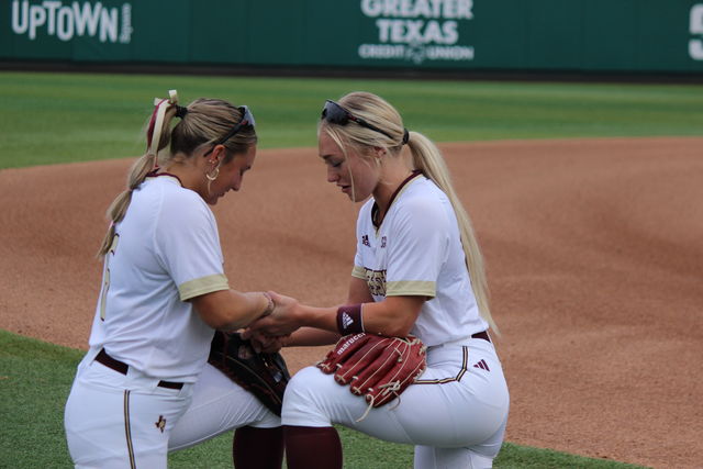 Texas State graduate right-handed pitcher Tori McCann (15) and senior outfielder Piper Randolph (11) pray together before the game, February 9, 2024, Bobcat Softball Stadium.
