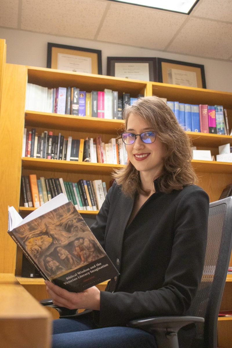 Assistant professor of English, Denae Dyck, poses with her book Biblical Wisdom and the Victorian Literary Imagination, Friday, Feb. 16, 2024, in Flowers Hall.