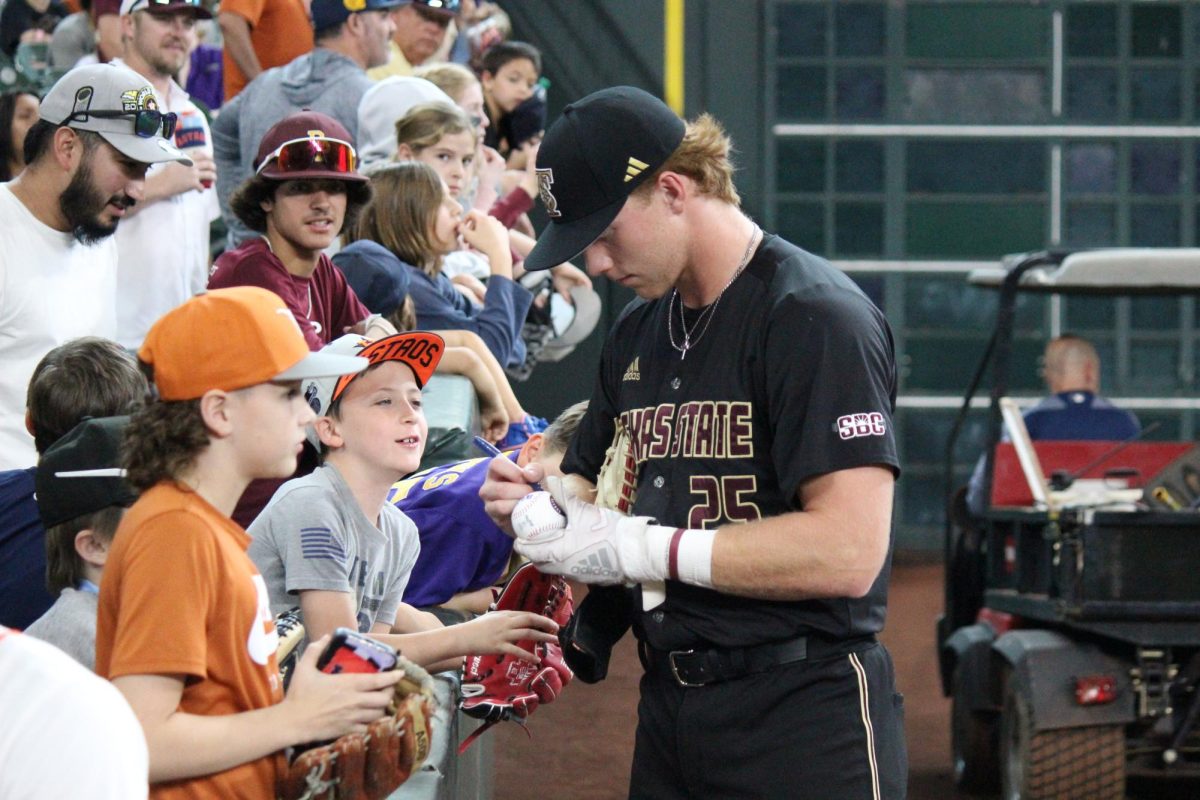 Texas State junior catcher Ian Collier (25) signs balls for children in the stands, March 3, 2024, Minute Maid Park.