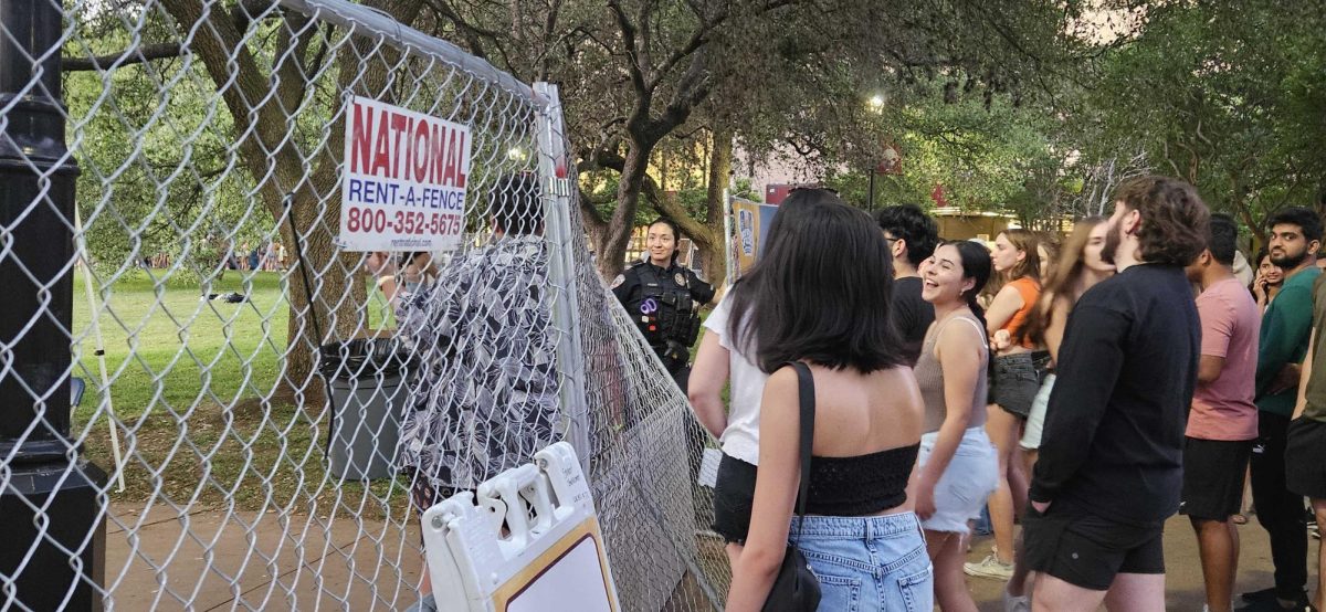 Spectators observe the torn down fence at River Fest while an official keeps guard, Thursday, April 11, 2024, at Sewell Park.
