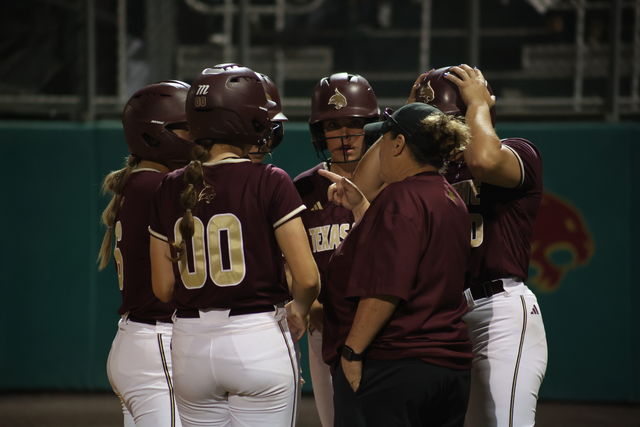 Texas State softball Head Coach Ricci Woodard gathers with some players during the game against Texas A&M, Wednesday, March 20, 2024, at Bobcat Softball Stadium.