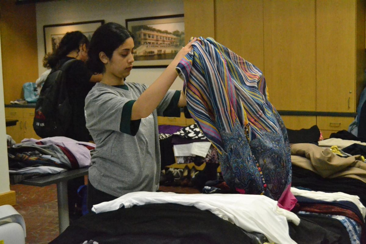 Pranesha Dangol, a civil engineering freshman and volunteer at the festival, folds clothes at the clothing swap, Saturday, April 20, 2024, at the Meadows Center in San Marcos.