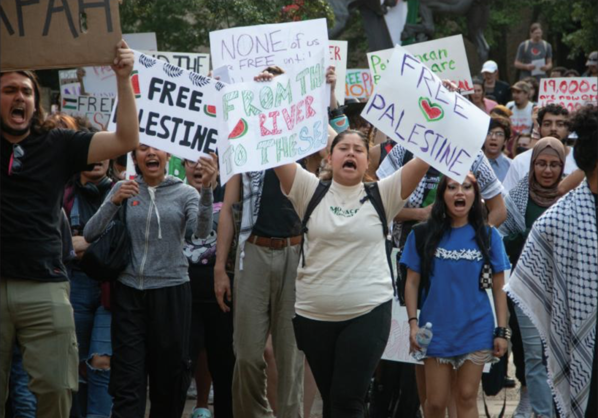 Supporters of the sit-in for Palestine hold up signs and march through The Quad Monday, April 29, 2024, to call for the removal of the Israeli flag from the Multicultural Lounge in Lampasas Hall.