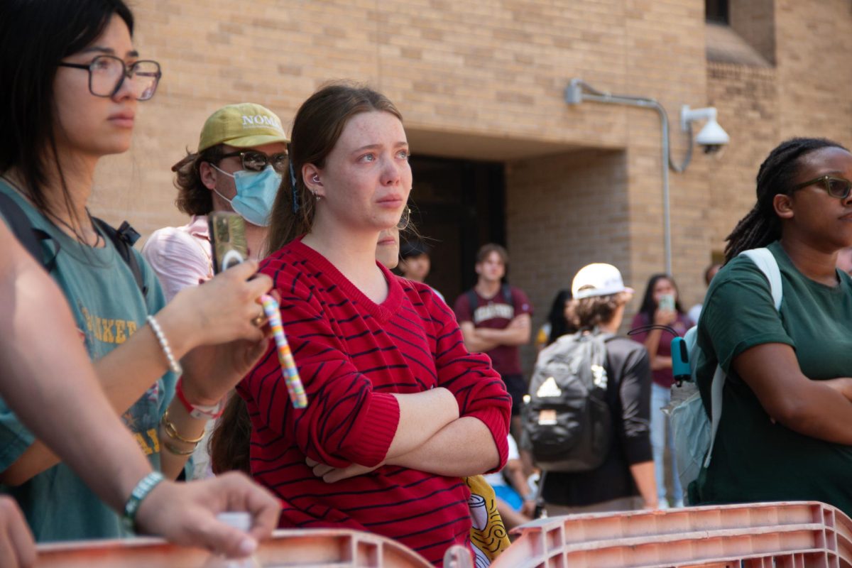 A woman, standing behind police barricades, tears up while watching speakers of the sit-in for Palestine on The Quad on Monday, April 29, 2024. 