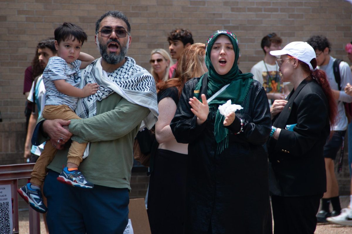 Amanda Smith stands next to a man holding a child on the edge of the crowd of the sit-in for Palestine on The Quad on Monday, April 29, 2024. 