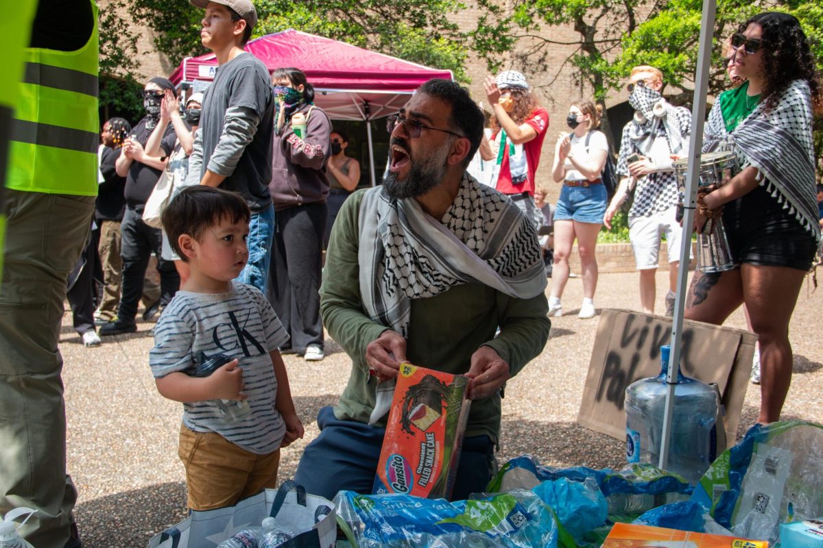 A supporter of the sit-in for Palestine opens a box of snacks for a young boy while cheering on at The Quad on Monday, April 29, 2024. 