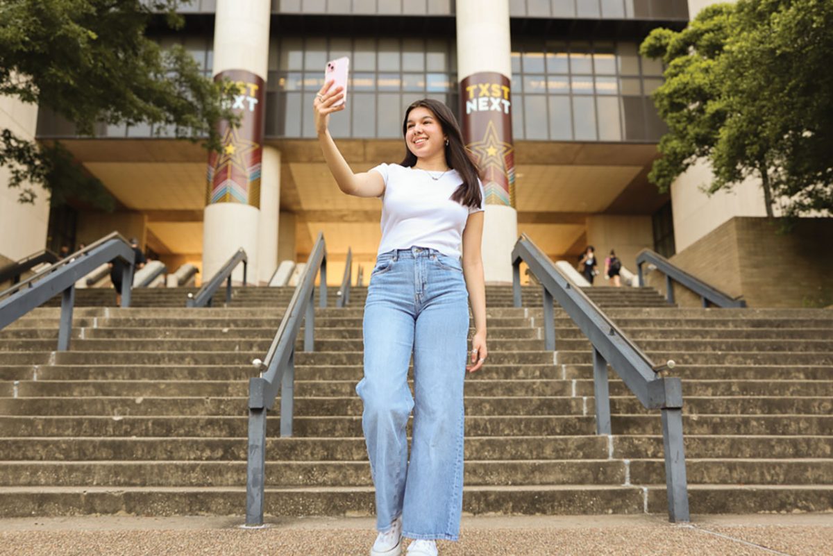 Interior design junior Stephanie Valdez records herself in front of the Alkek Staircase, Friday, April 19, 2024, at Texas State University.