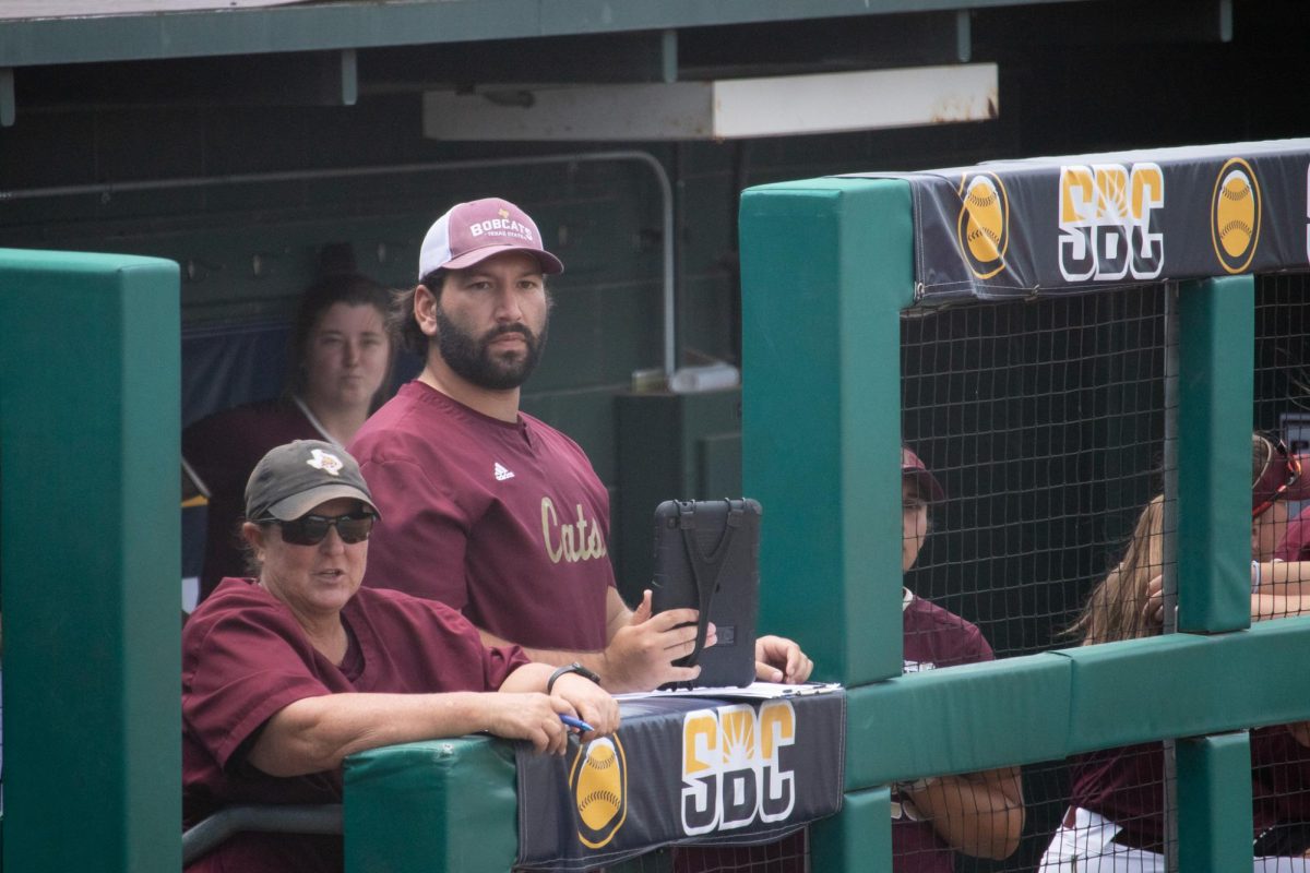 Texas State pitching coach Josh Trevino watches from the dugout during the Sun Belt tournament quarterfinal round game against Marshall, Thursday, May 9, 2024, at Bobcat Softball Stadium. 