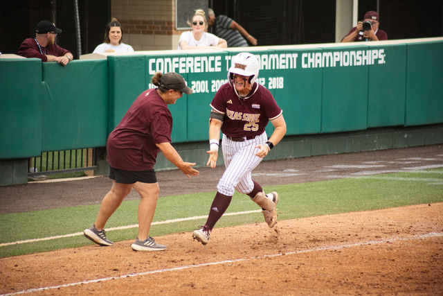 Texas State senior utility JJ Smith (25) high-fives Head Coach Ricci Woodard while running home during the Sun Belt tournament championship game against Louisiana-Lafayette, Saturday, May 11, 2024, at Bobcat Softball Stadium.