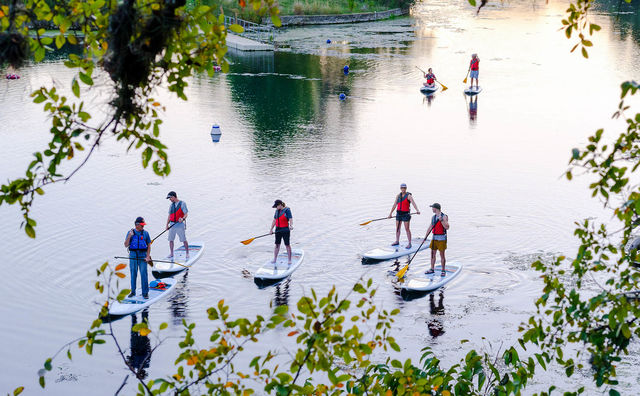 A standup paddleboarding tour group paddles across the water, Sunday, November 6, 2022, at Spring Lake. Photo courtesy of the Meadows Center for Water and the Environment.
