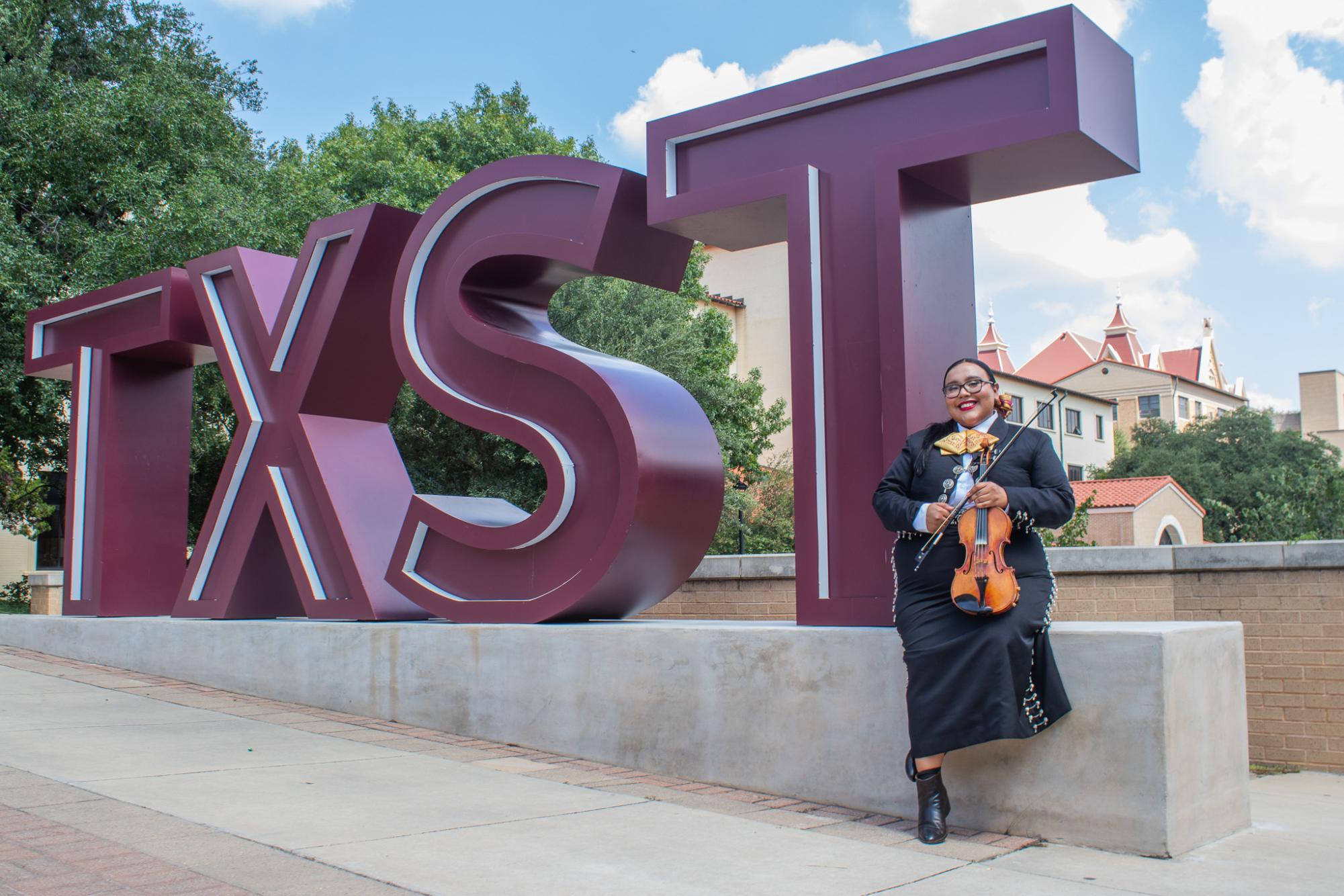 Social work junior Abby Garcia sits in front of the TXST sign on campus, Monday, Sept. 16, 2024, at Bobcat Trail.