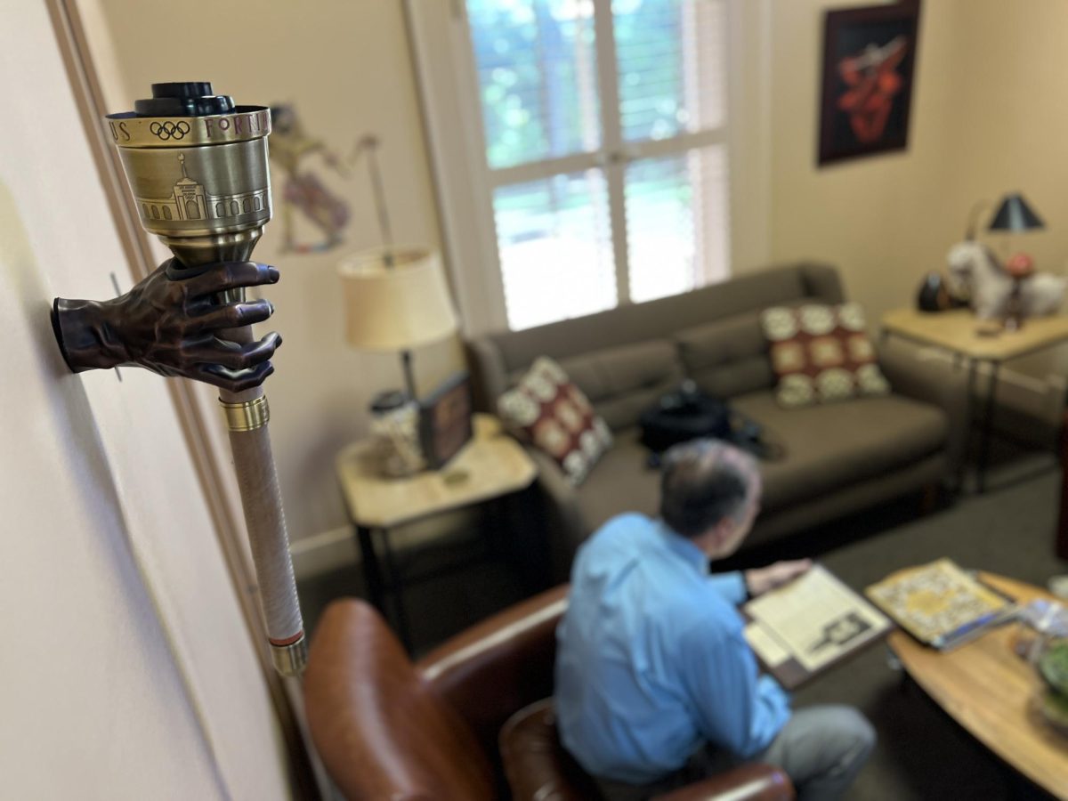 Texas State Dean of the College of Fine Arts and Communication, John Fleming, sits below his Olympic torch, Tuesday, August 27, 2024, in Old Main. 