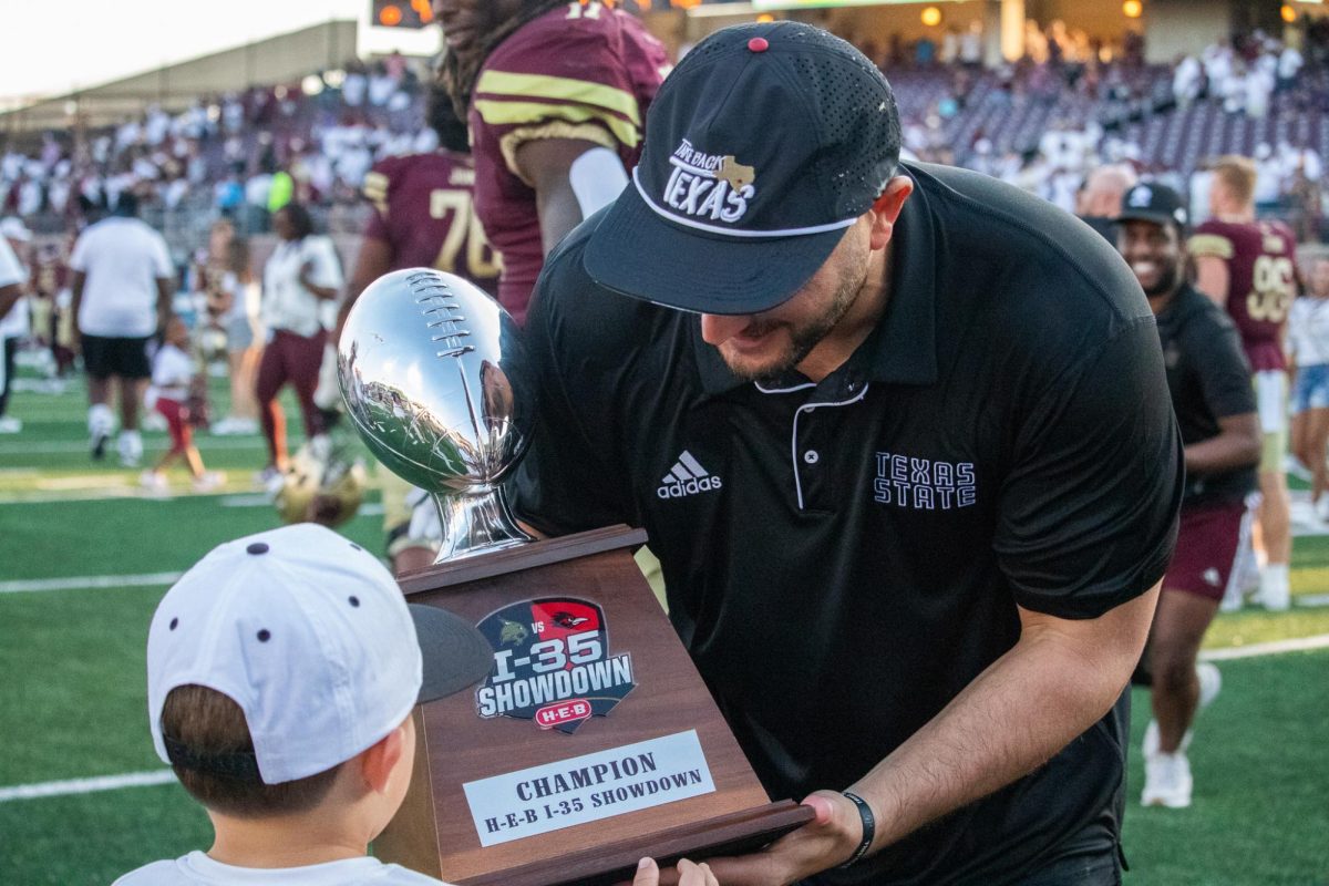 Texas State Head Coach G.J. Kinne holds the I-35 Showdown trophy with his son after defeating UTSA. Saturday, Sept. 7, 2024 at Jim Wacker Field at UFCU Stadium.