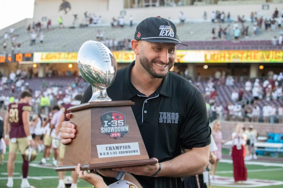 Texas State Head Coach G.J. Kinne holds the I-35 Showdown trophy with his son after defeating UTSA 49-10, Saturday, Sept. 7, 2024, at UFCU Stadium.