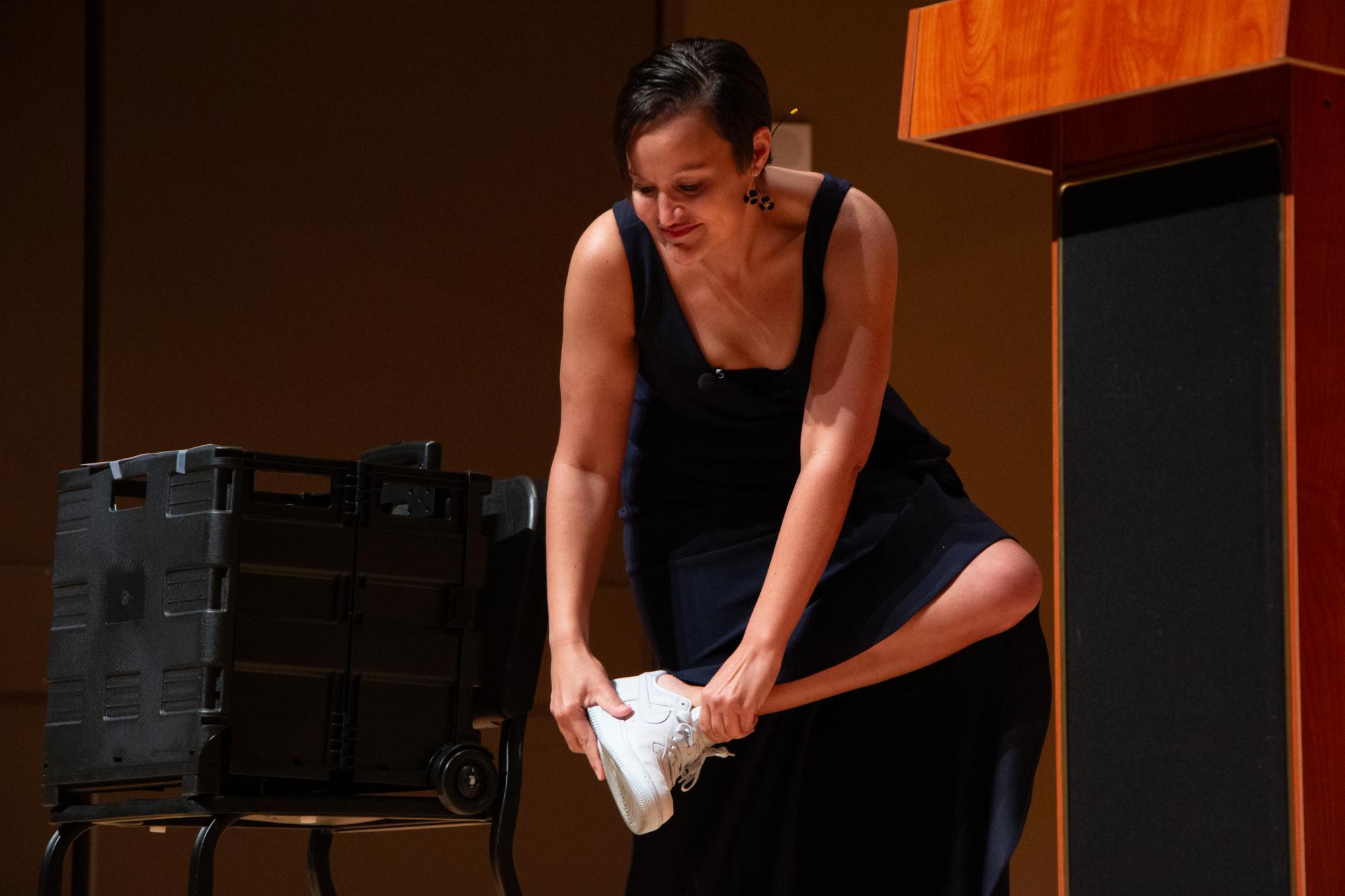 Navy veteran and nontraditional student Jessica Ary places a white shoe on while describing the roles she had to fill as a single parent and student during her Star Stories speech, Wednesday, Oct. 23, 2024, at the Performing Arts Center.