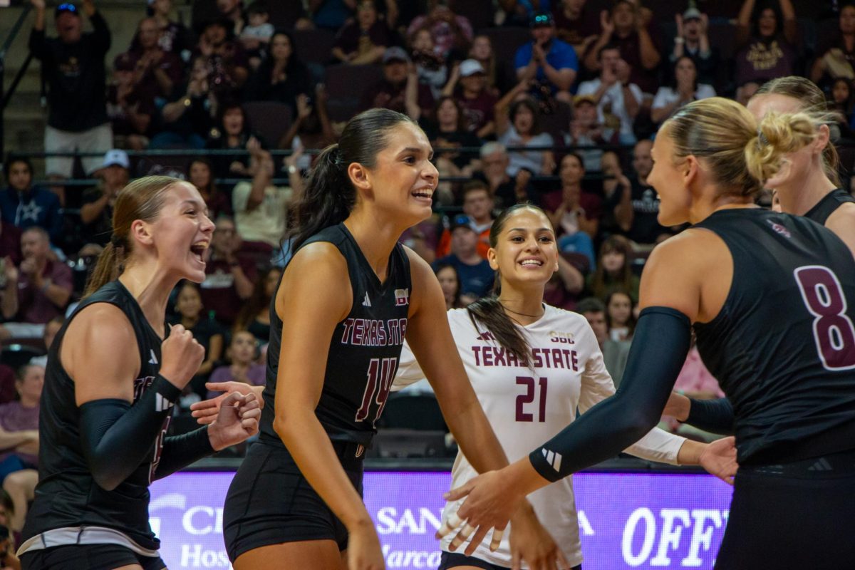 Texas State setter Ryann Torres (14) rushes to celebrate a scored point with outside hitter Samantha Wunsch (8) and other team members on Friday, Oct. 4, 2024, at Strahan Arena.