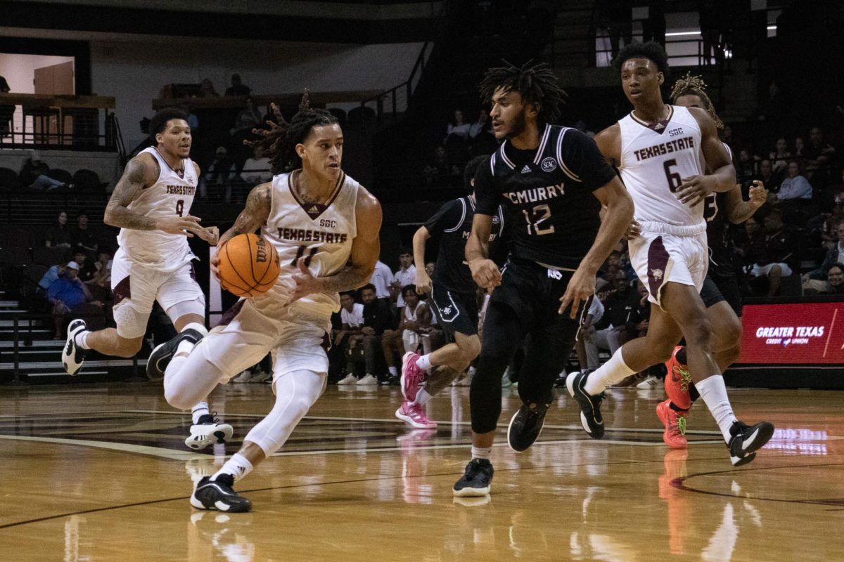 Texas State sophomore guard Kaden Gumbs (11) dribbles the ball past a McMurry defender, Friday, Nov. 8, 2024, at Strahan Arena.