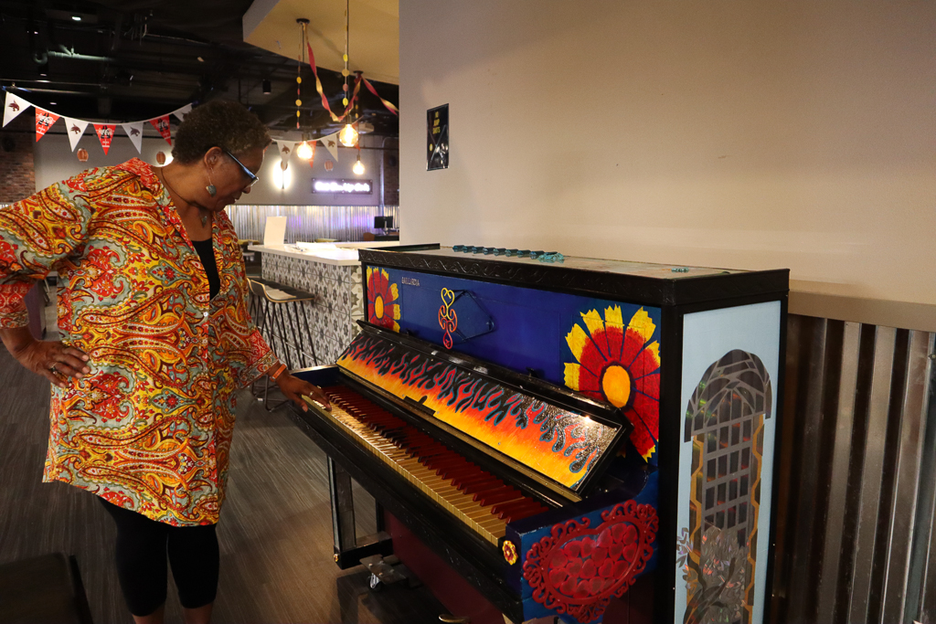 Interdisciplinary studies alumna Glynis Christine shows off the piano she painted, Friday, September 27, 2024, at George’s in the LBJ Student Center.