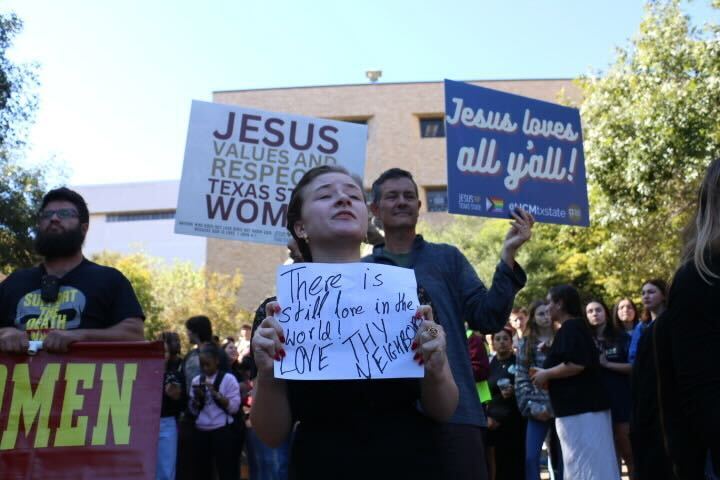 Texas State student holds sign reading "There is still love in the world," counter protesting demonstration Wednesday, Nov. 6, 2024, at the Stallions statue.