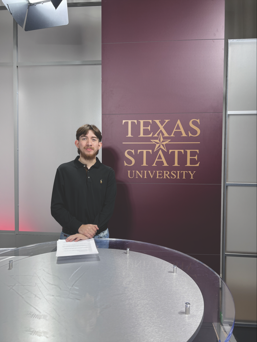 Multimedia Editor Kobe Arriaga poses in front of a Texas State image, Friday, Nov. 22, 2024, at Live Oak Hall.