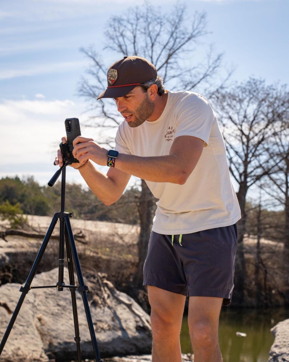 Business management alumnus John Sorsby does a behind-the-scenes photoshoot of creating his videos, Tuesday, Feb. 10, 2024, at McKinney Falls State Park in Austin. Photo courtesy of Madison Wickham.