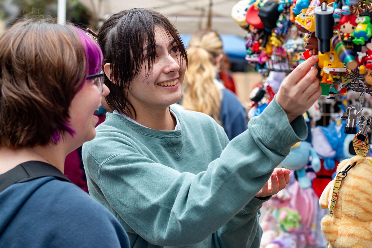 Texas State health sciences sophomore Quinn Brasher (Right) and biochemistry sophomore Alissa Short (Left) preview keychains and trinkets sold at Market Day, Wednesday, Feb. 12, 2025, on the Quad. The variety of vendors' goods included food, jewelry, crocheted goods, knick knacks and more.