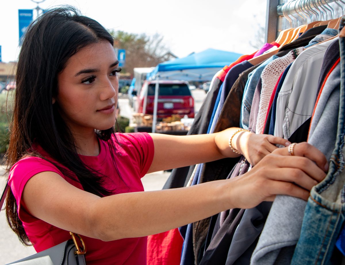 Biology freshman Alexandra Avilez rifles through a rack of resell clothes during the San Marcos Valentine’s Craft & Vendor Market, Saturday, Feb. 8, 2025, at the Tanger Outlets. 