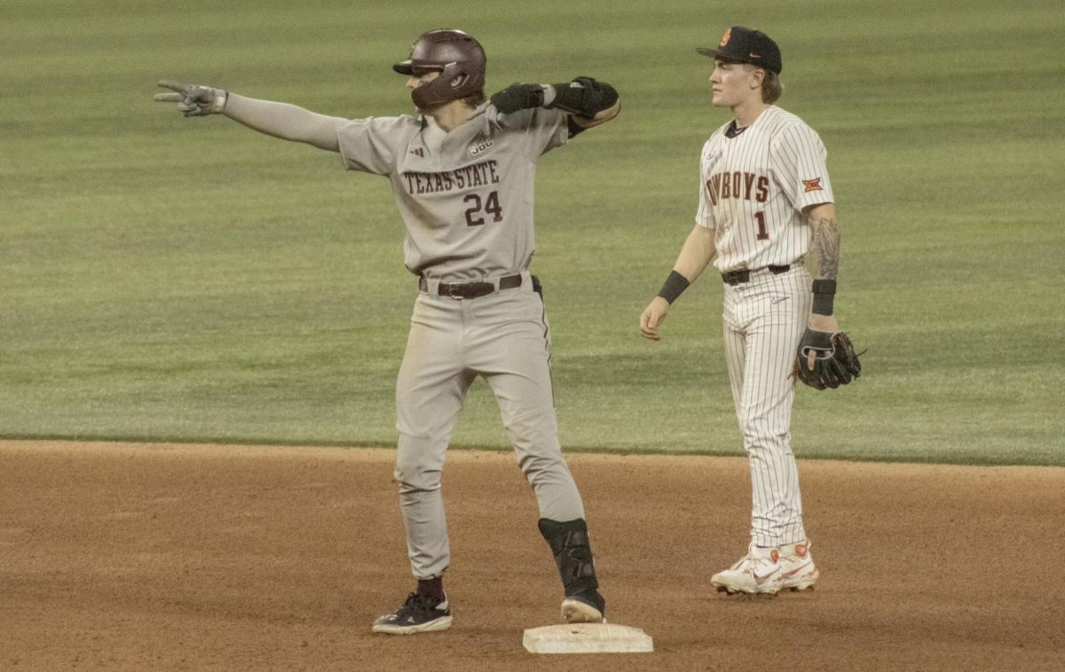 Utility player Ethan Farris (24) points toward the Texas State dugout after hitting a double against Oklahoma State on Tuesday, Feb. 18, 2025, at Globe Life Field in Arlington. Bobcats won 4-2.