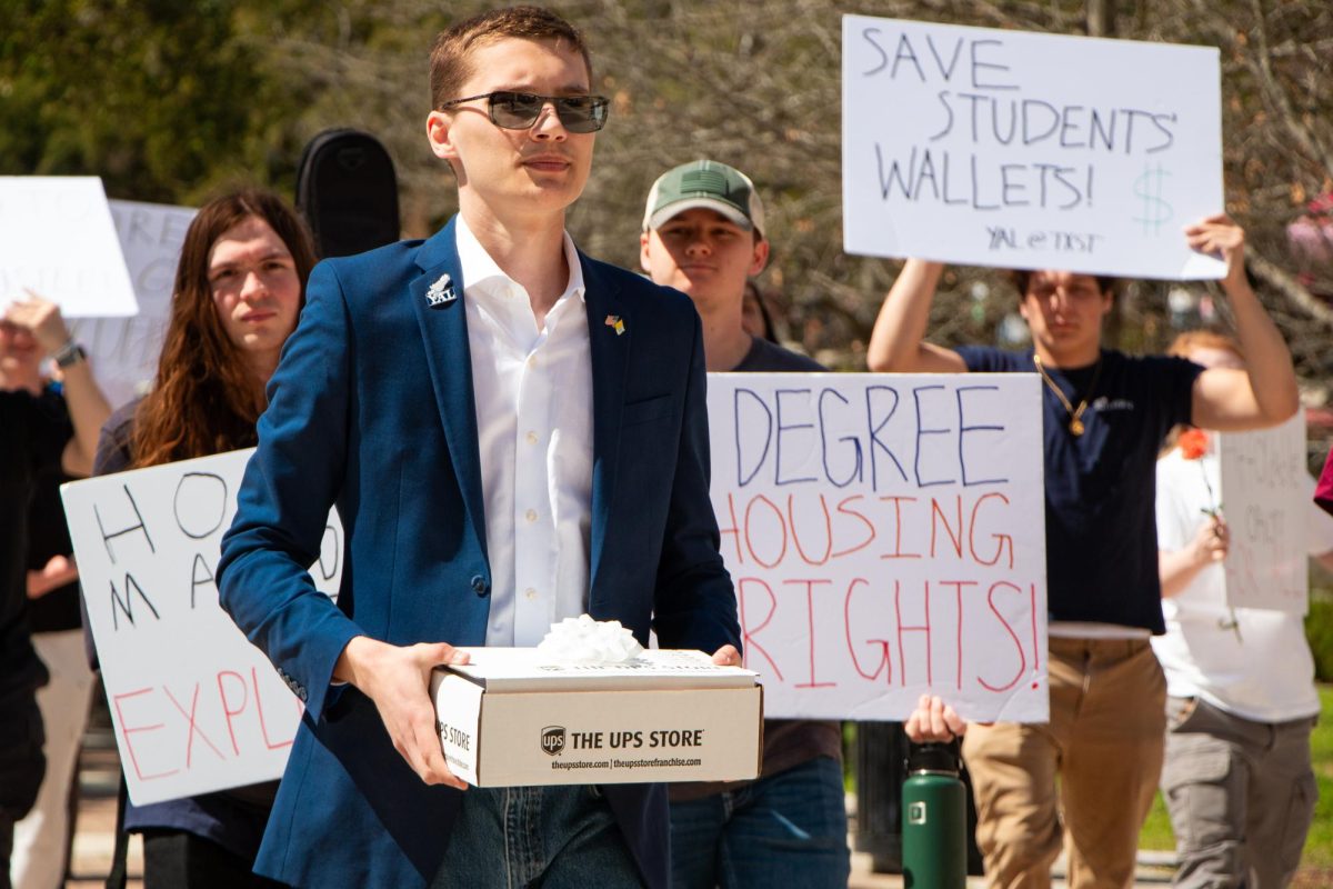 TXST mechanical engineering technology senior Eric Pinteralli leads a protest against the requirement for freshmen to live on campus to deliever a box of signed petitions to TXST President Kelly Damphousse's office, Tuesday, March 4, 2025, outside of Commons Dining Hall.