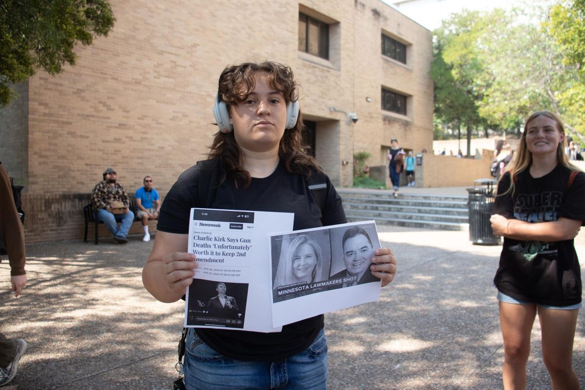 A counter protester to the Charlie Kirk memorial shows off their signs, Monday, Sept. 15, 2025 on the Quad.