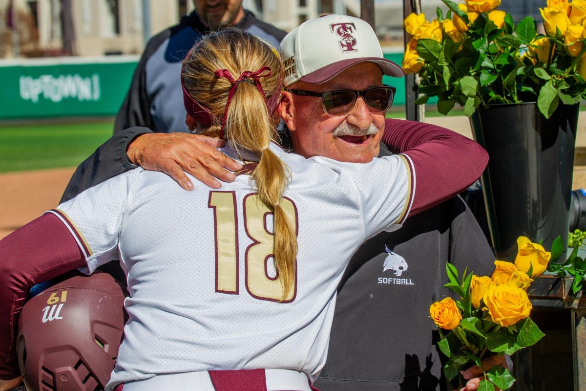 Texas State freshman pitcher Chesney Davis (18) hugs local photographer Peter Vives better known as Photo Pete, Sunday, Feb. 15, 2026, at Bobcat Stadium. Vives has covered women’s sports at Texas State with a focus on softball since 2007.
