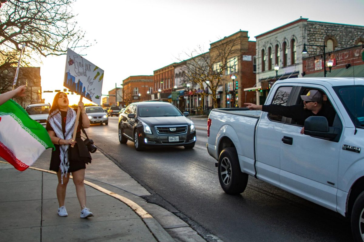 An onlooker yells at Marivelle Olgin (left) during the Party for Socialism and Liberation protest against the U.S.-Iran conflict, Monday, March 2, 2026, at the Hays County Courthouse