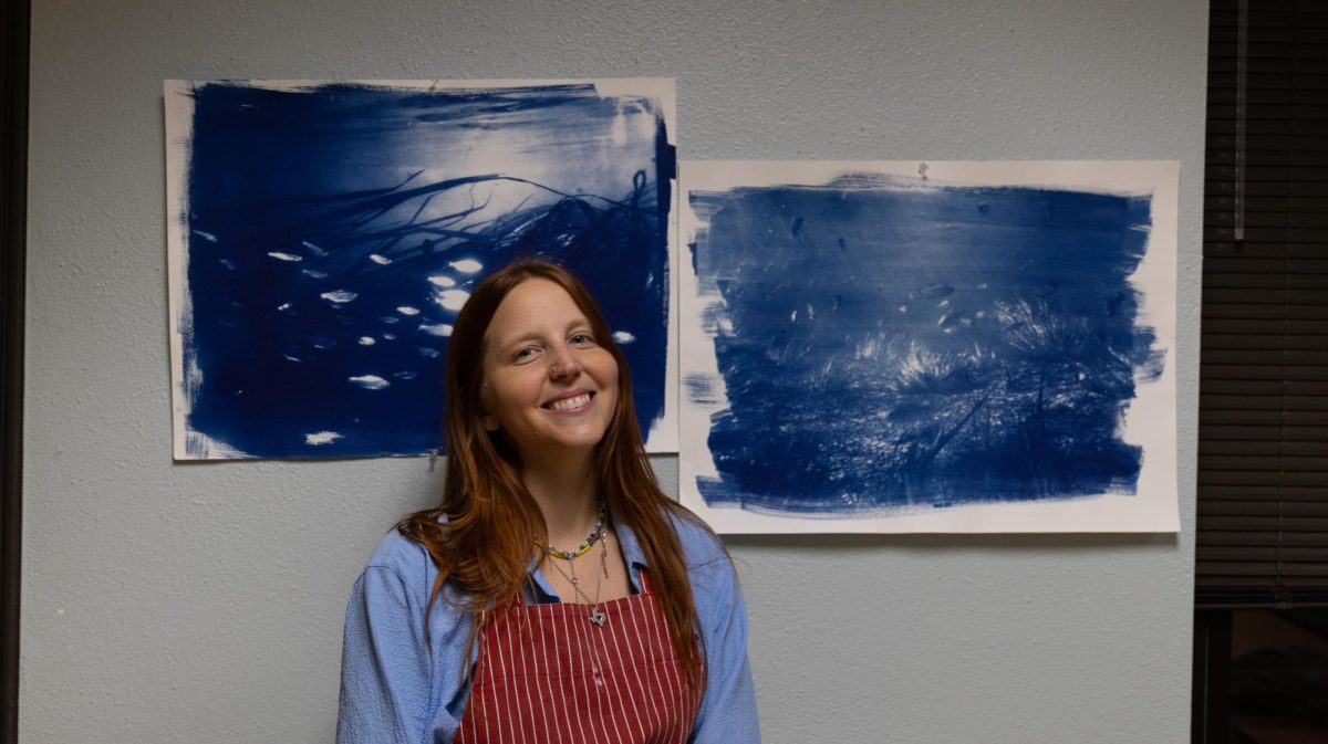 Meggie Emerick, manager at 1 Hr Film Lab and founder of San Marcos Photo Friends, stands behind her cyanotypes created using digitally enlarged film negatives at The Night of Ideas in the Taylor Murphy building on March 27th, 2026. Meggie hosted a workshop based on the medium of a cyanotype where people worked creatively and collaboartively to create images.