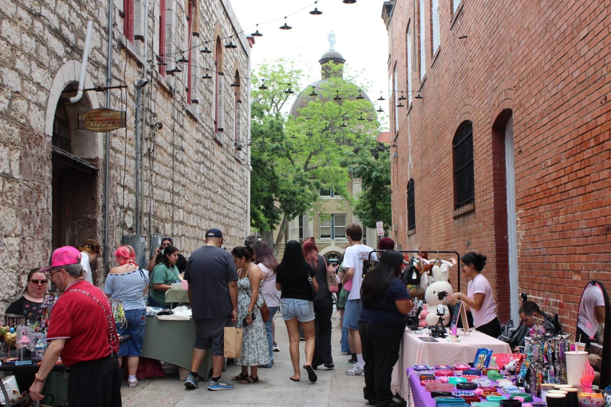 People walk through the Trinket Girl Market, Sunday, April 26, 2026, at Kissing Alley on 121 E. Hopkins St.