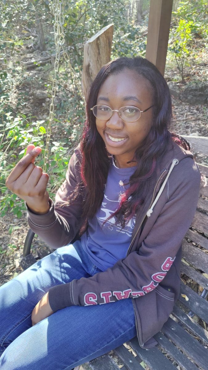 Life and Arts Editor Carlene Ottah makes a finger heart sign during a Friendsgiving, Saturday, Nov. 8, 2025, at Slumber Falls Camp in New Braunfels. Photo courtesy of Dev Davis.